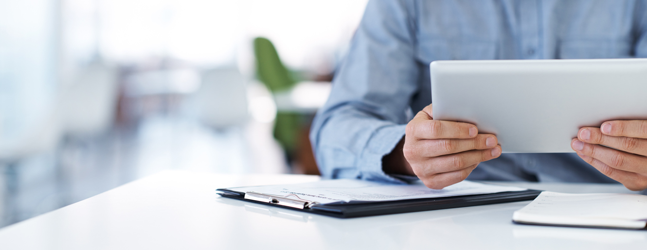 Man holding tablet at desk.